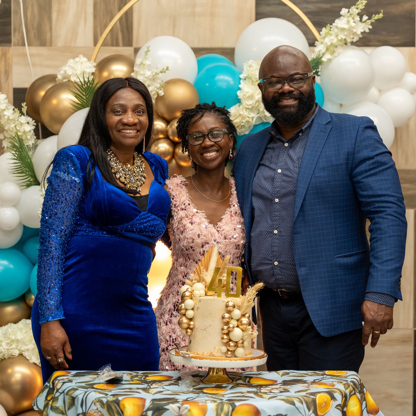 Hilda with two guests behind her gold-and-white 40th birthday cake