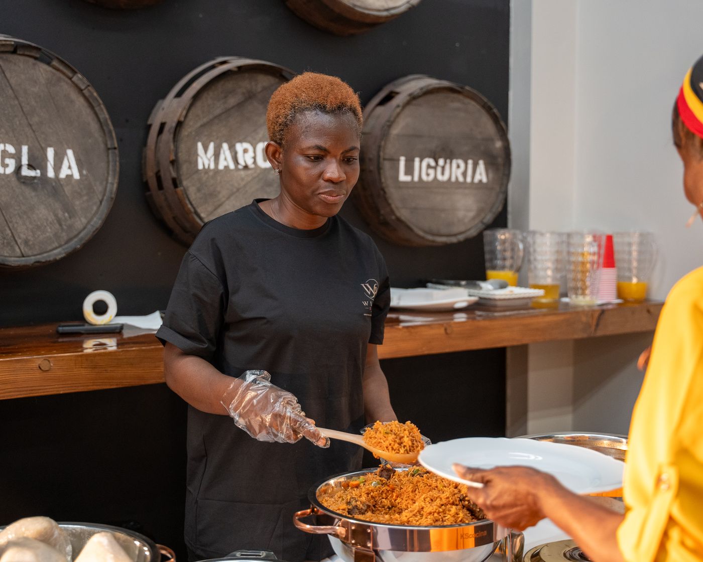 A WillBe Events server spooning jollof rice for a guest