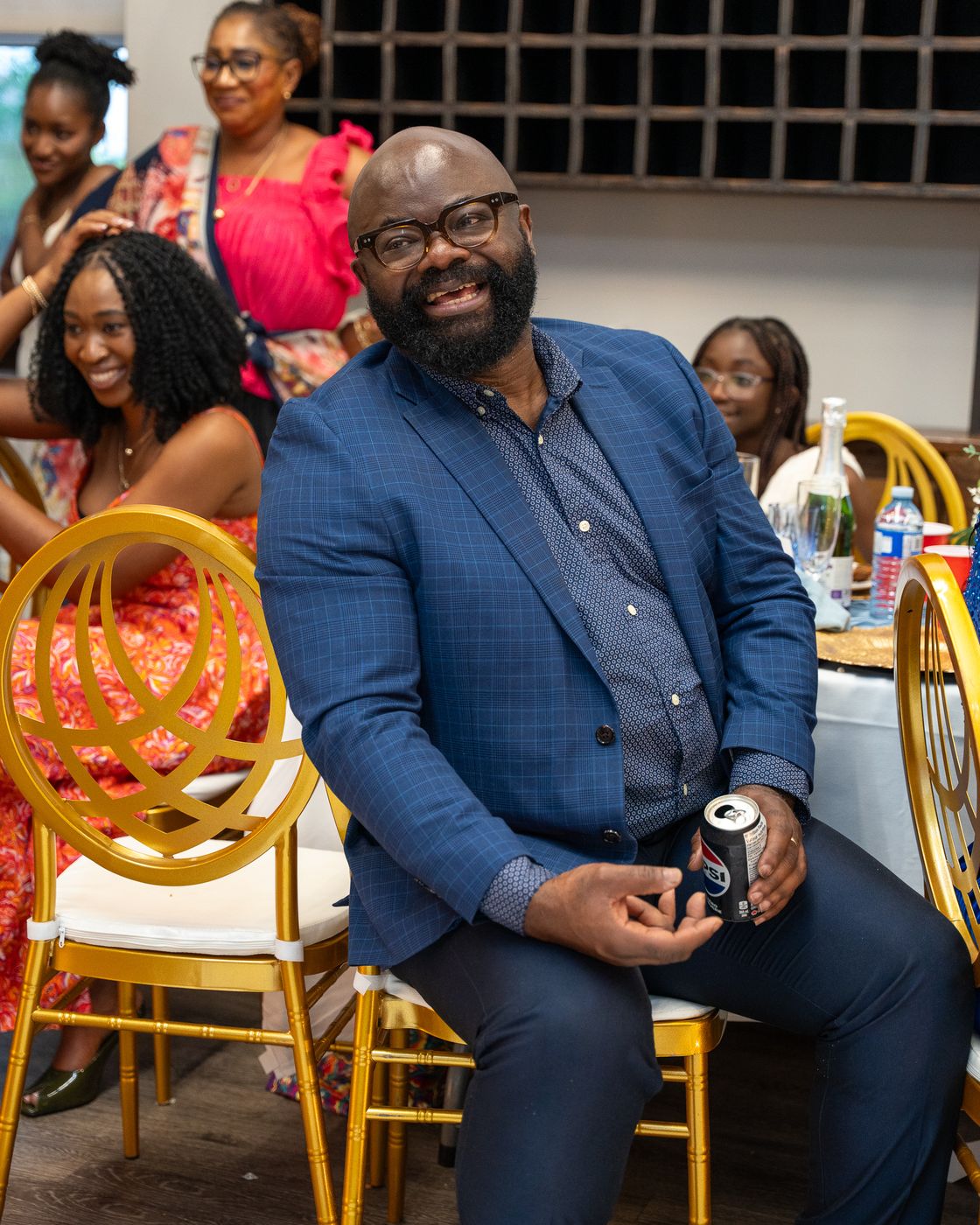 A guest in a blue check blazer laughing at his table