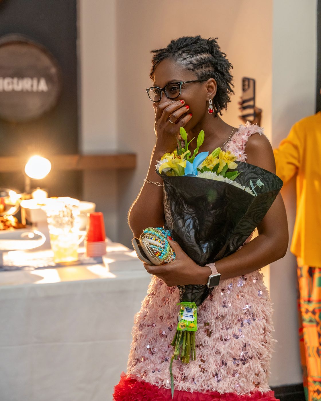 Hilda covers her mouth in surprise, holding her bouquet