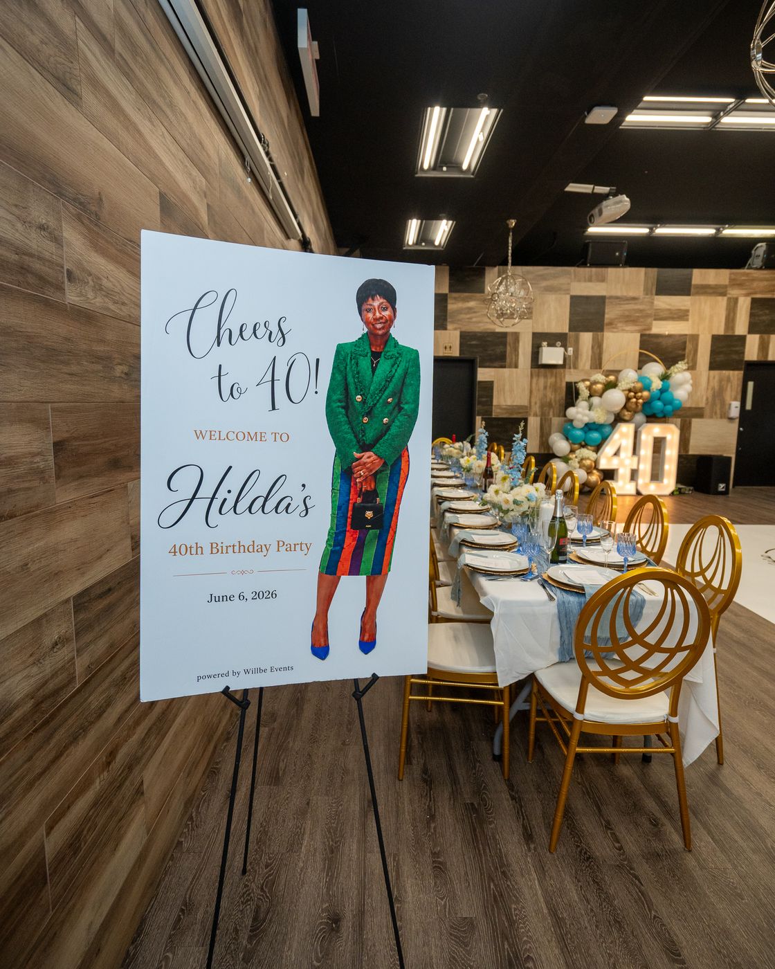 Cheers to 40 welcome sign for Hilda's 40th birthday party beside a table set with gold chairs