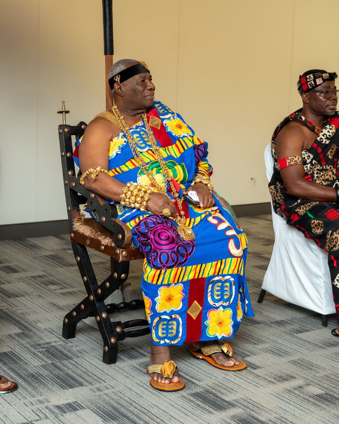 A chief in kente and gold regalia seated