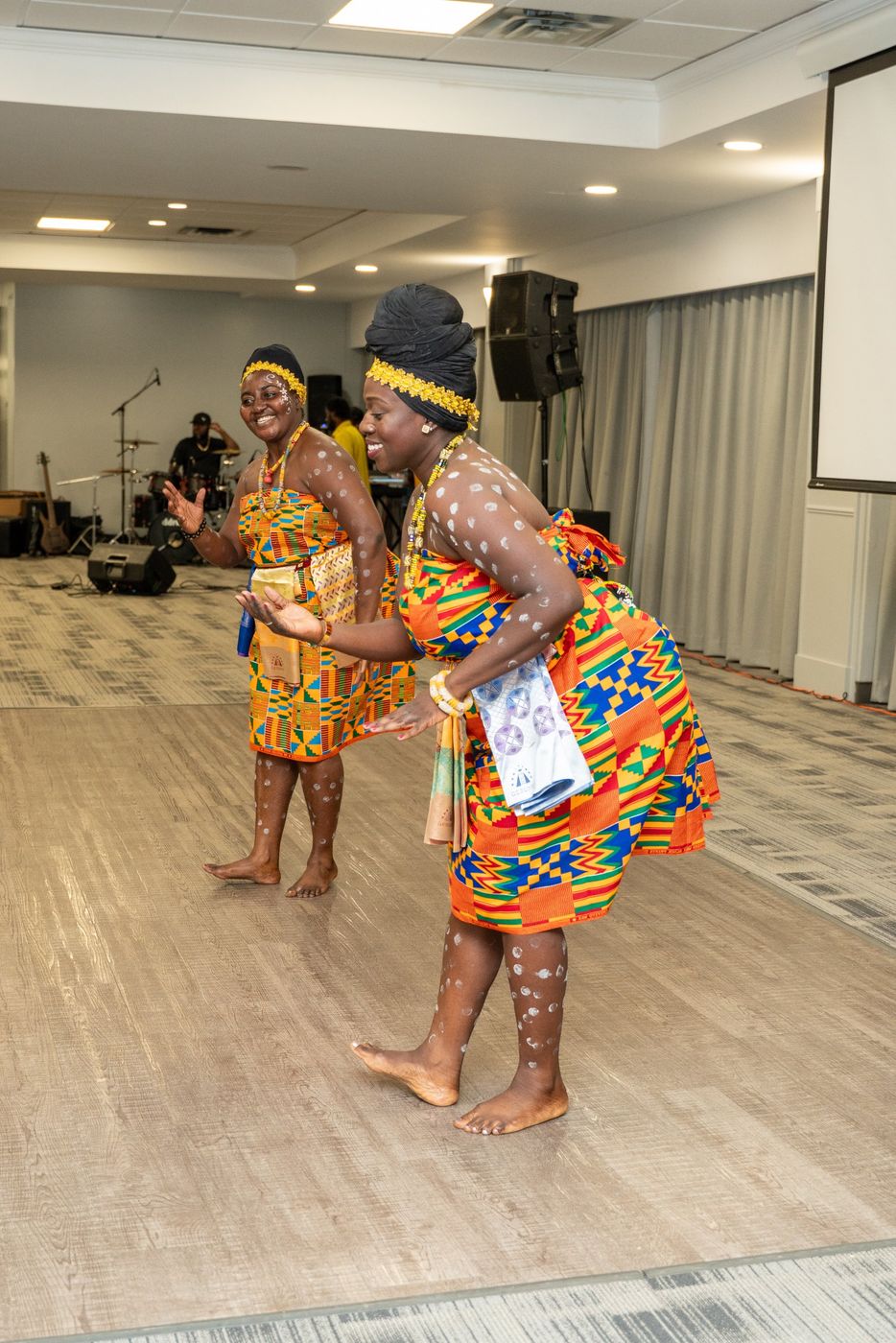 Two dancers in kente performing a traditional dance