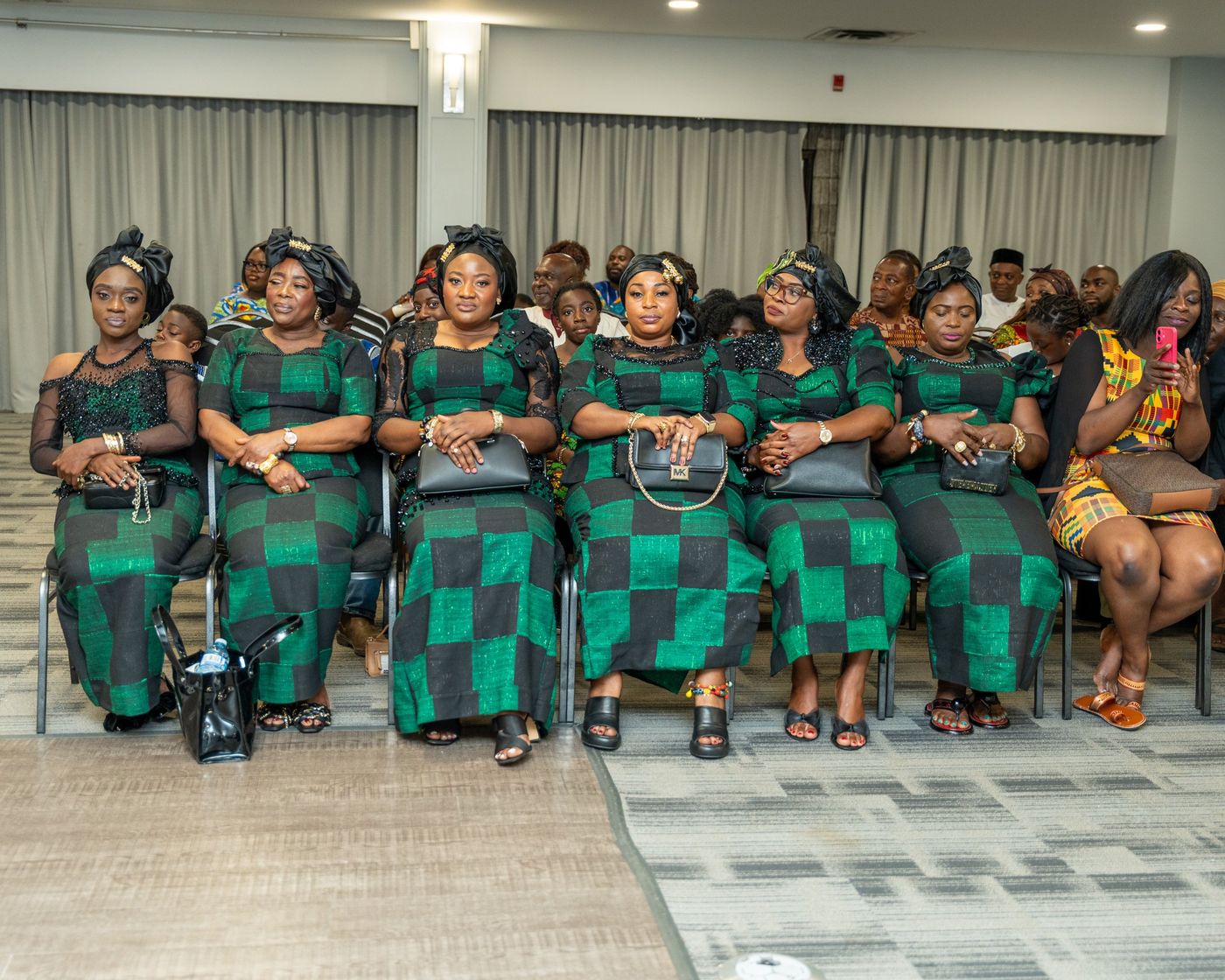 A group in matching green and black outfits seated in the front row