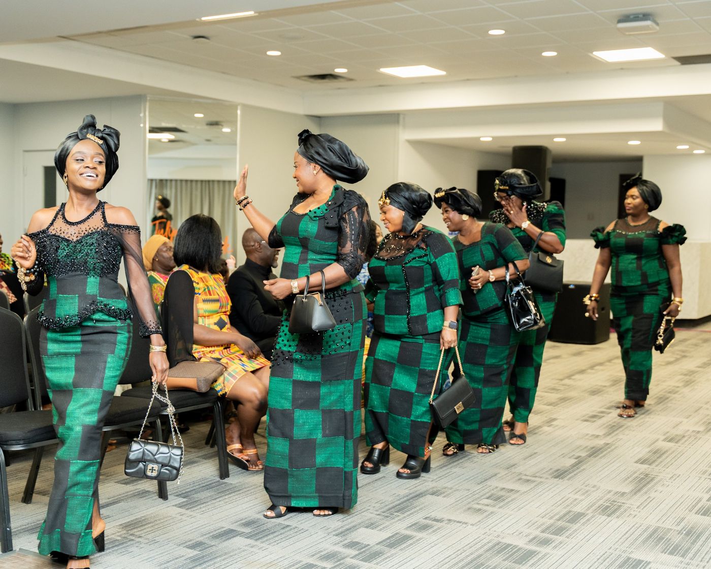 Women in matching green and black outfits waving as they enter