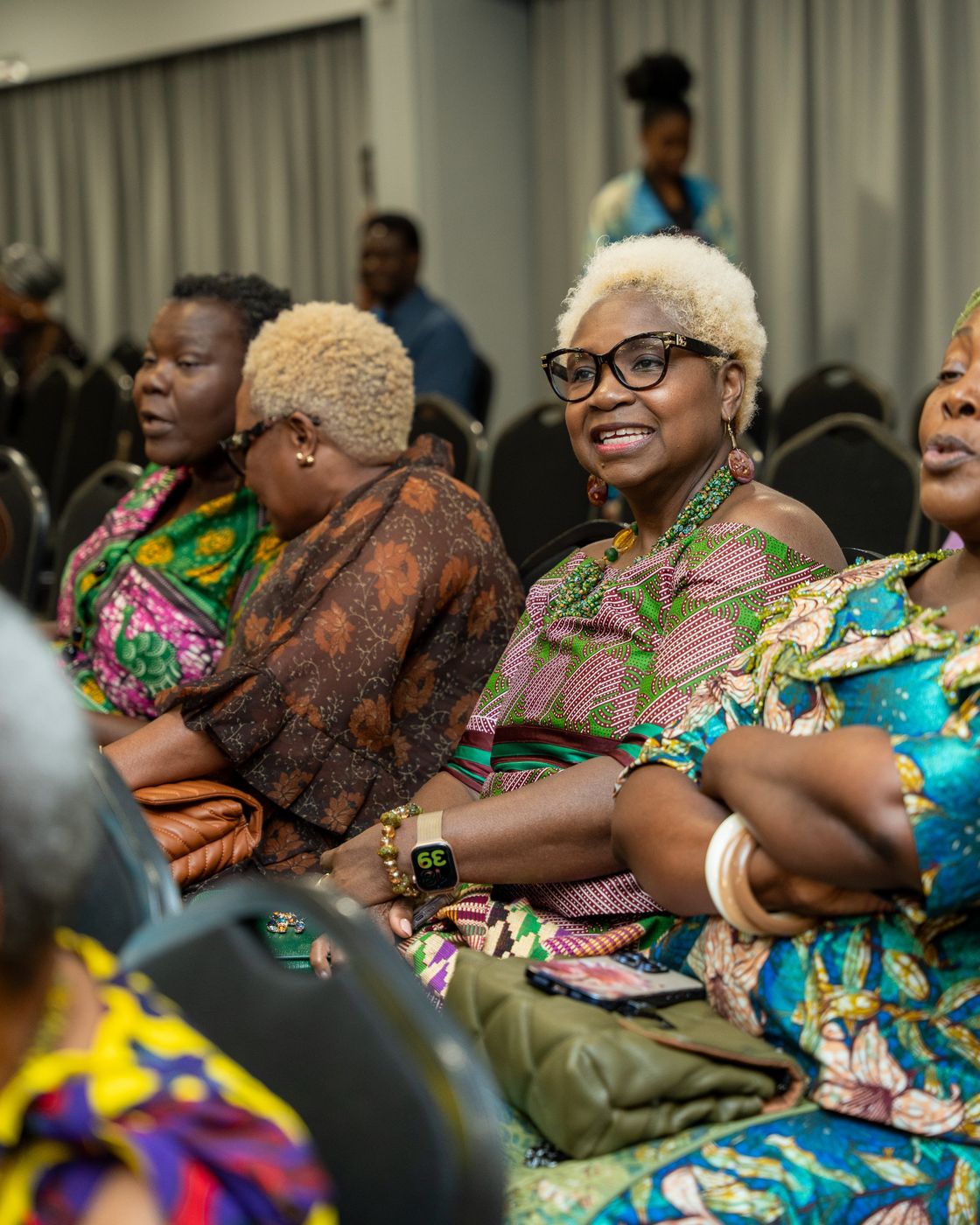 Guests in African print smiling in the audience
