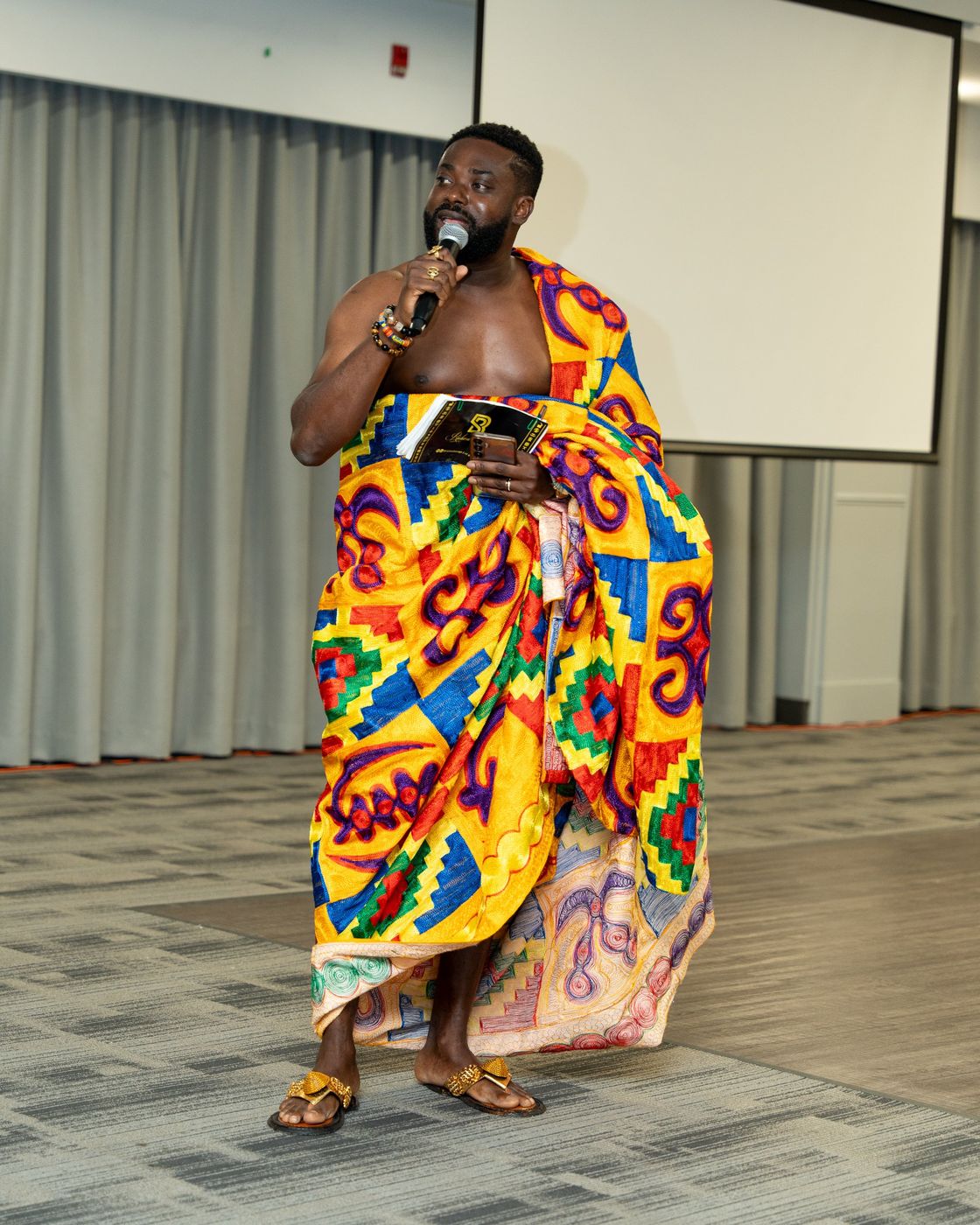 The MC in kente cloth speaking into the microphone