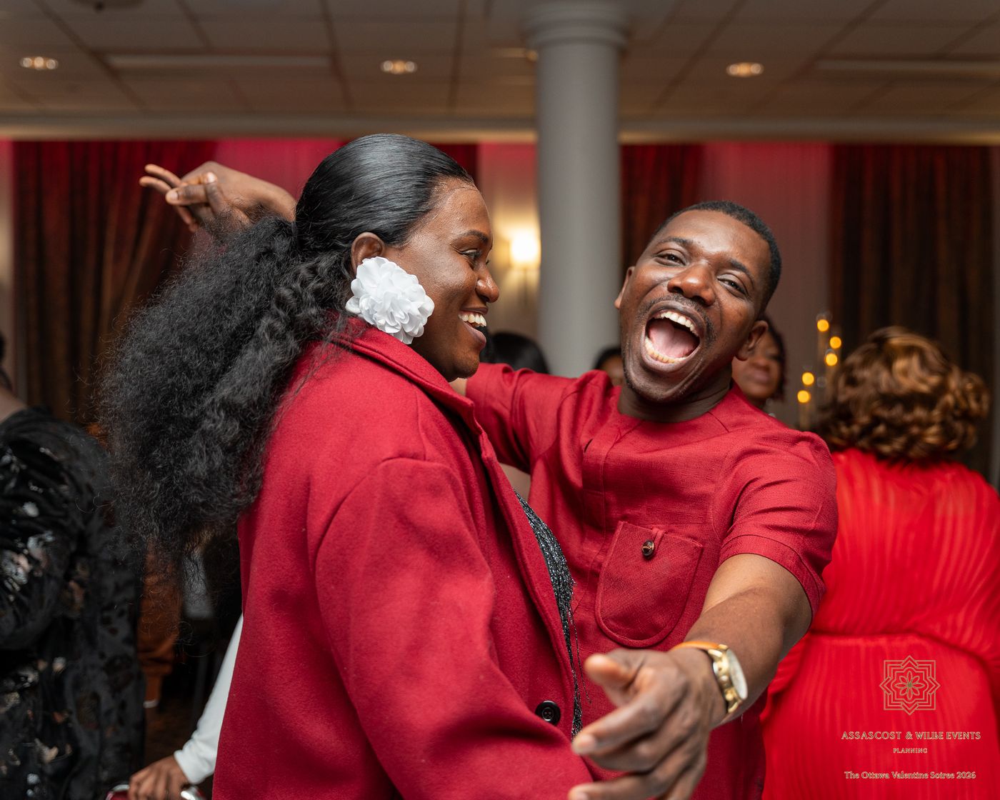 Two guests in red laughing as they dance