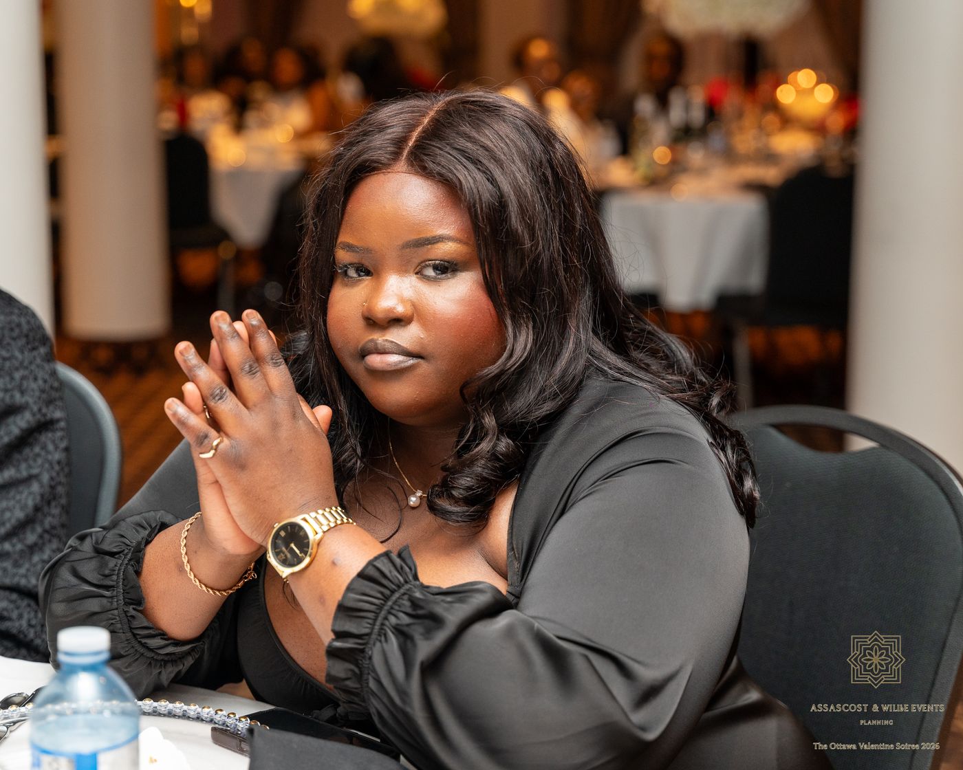 A guest in a black dress with her hands together at the table