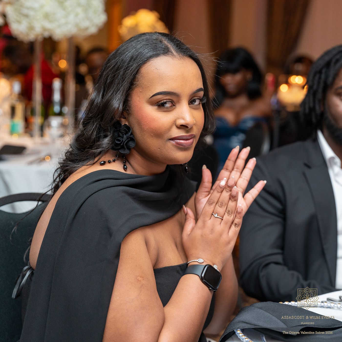 A guest in a black dress with rose earrings looking over her shoulder